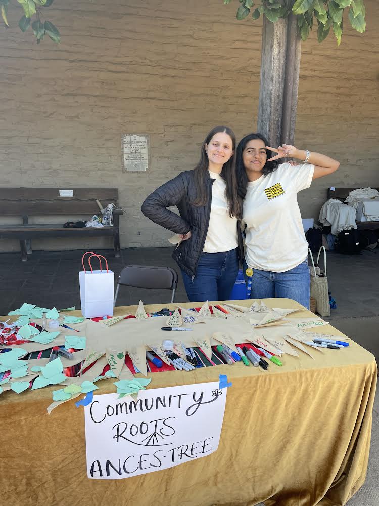 San Marcos Ethnic Studies Club members seniors Zoe Javanbakht and Kavya Suresh pose behind their table, which features an Ances-Tree. Attendees were encouraged to write an important part of their upbringing and background on a paper root and tape it to the tree. 